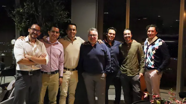 Parte del grupo posando en el SkyPriority de la torre The Sky, con los ventanales y la ciudad de noche al fondo.